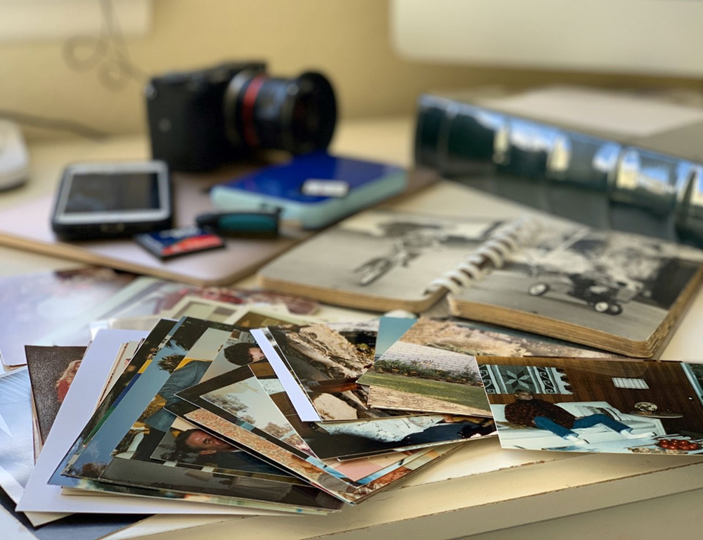 Printed family photos, albums and a backup drive on a work table