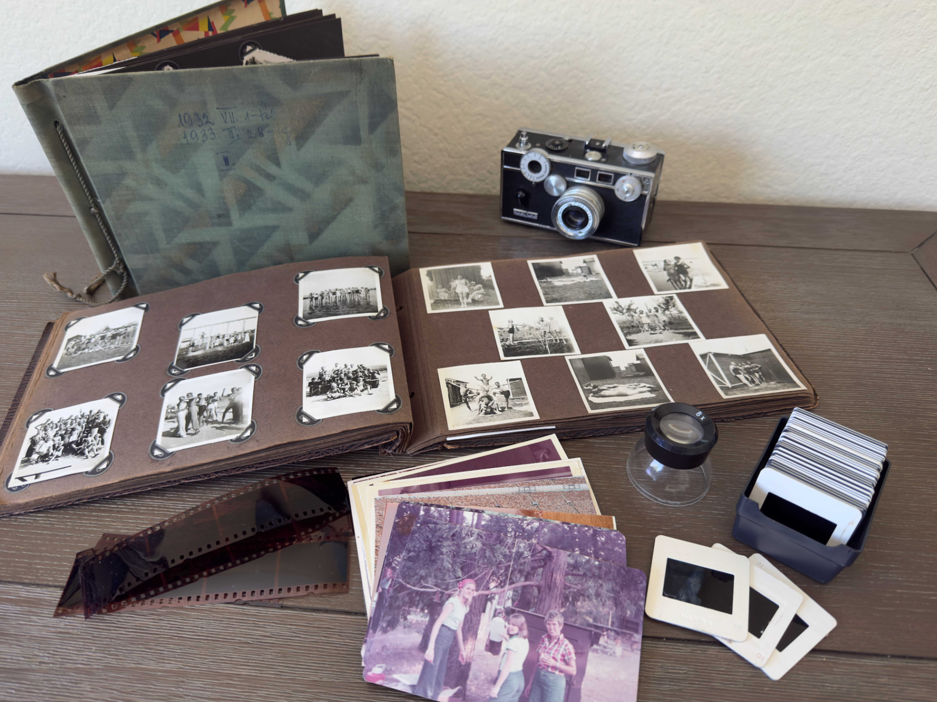Vintage photo albums, negatives, slides, and a film camera laid out for scanning
